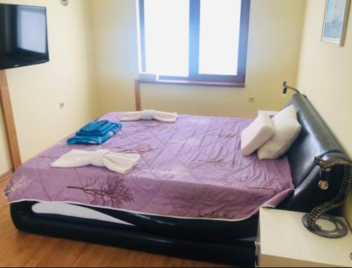 a bed in a room with a purple comforter at Сънрайз Данаилов in Obzor