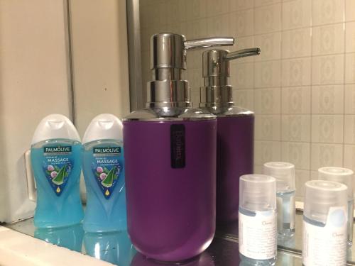 eine Badezimmertheke mit einem lila Seifenspender und Flaschen in der Unterkunft Bellini Apartment's in Novara