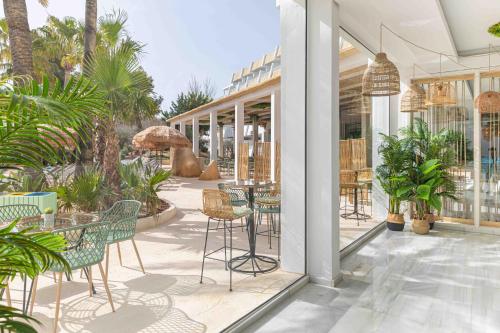 d'une terrasse avec des tables, des chaises et des palmiers. dans l'établissement MarSenses Rosa del Mar Hotel & Spa, à Palma Nova