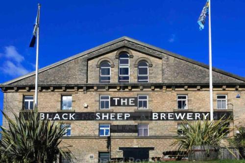 a brick building with two flags in front of it at Brewers Den a Beautiful 1-Bed Apartment in Masham in Ripon