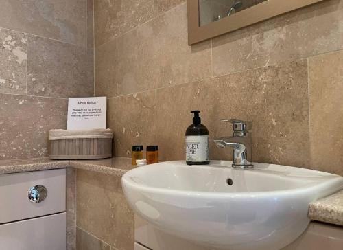 a bathroom sink with a bottle of alcohol on it at Brewers Den a Beautiful 1-Bed Apartment in Masham in Ripon