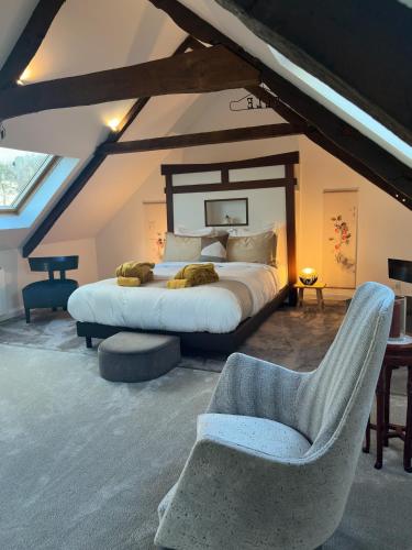 une chambre avec un lit et une chaise dans un grenier dans l'établissement Demeure du Porzou, chambres d'hôtes de charme dans demeure d'exception, parc paysager, spa, massages, proche Paimpol, classé 4 épis, à Yvias