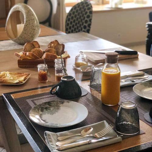 una mesa con un plato de pan y zumo de naranja en Demeure du Porzou, chambres d'hôtes de charme dans demeure d'exception, parc paysager, spa, massages, proche Paimpol, classé 4 épis, en Yvias