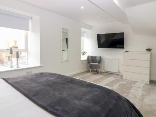 a bedroom with a bed and a tv and a chair at Craignure in Banff