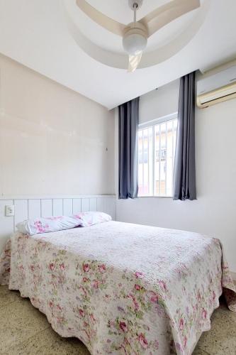 a bedroom with a bed with a floral bedspread and a window at Apartamento completo no centro de Belém, próximo de tudo! in Belém