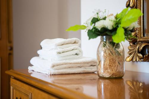 une poignée de serviettes sur une table avec un vase de fleurs dans l'établissement Casa Erzinio, à Guarcino