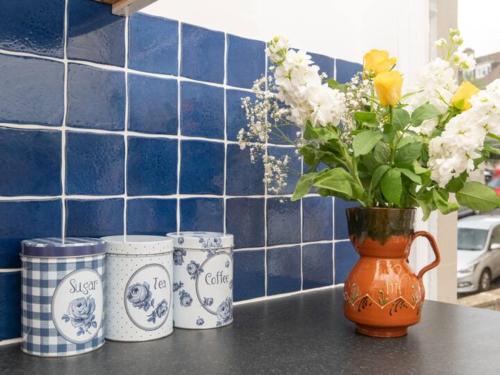 an orange vase with flowers in it on a counter at Central 2 bedroom flat with parking - Pass the Keys in Bath