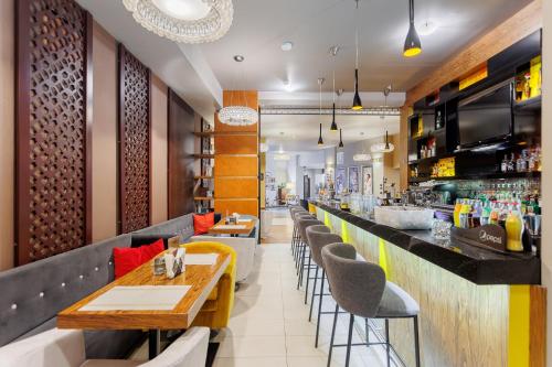 a restaurant with a long bar with chairs and tables at Hotel Tarnovia in Tarnów