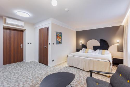 a hotel room with a bed and two chairs at Hotel Tarnovia in Tarnów