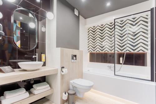 a bathroom with a toilet and a sink and a tub at Hotel Tarnovia in Tarnów