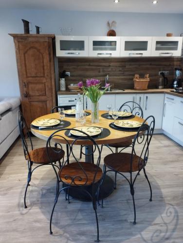 une cuisine avec une table, des chaises et des fleurs. dans l'établissement les Seilles de Clovis, à Entremont-le-Vieux