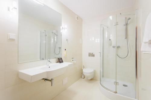 a white bathroom with a sink and a shower at Hotel Tarnovia in Tarnów