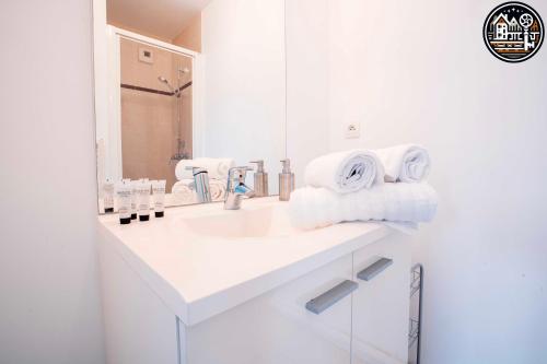 a white bathroom with a sink and a mirror at rouen gare logement avec parking in Rouen