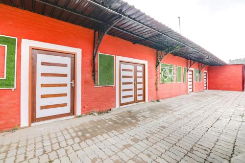 un edificio rojo con dos puertas laterales en OYO Flagship Aadya Greens en Juhi Bari
