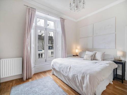 a white bedroom with a large bed and a window at Chic cosy Flat in Central London Pass the Keys in London