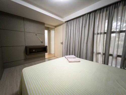a bedroom with a bed and a large window at Apartamento Central Wifi 300 Megas Excelente MC44 in Maringá
