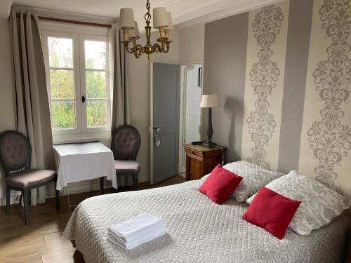 エクモヴィルにあるLes chambres d'hôtes Le Val d'Honfleurのベッドルーム1室(赤い枕2つ付きのベッド1台付)