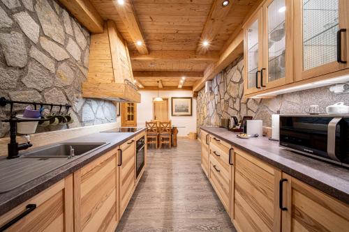 a kitchen with wooden cabinets and a stone wall at Tatrachalet Lomnica Rent in Vysoke Tatry - Tatranska Lomnica.