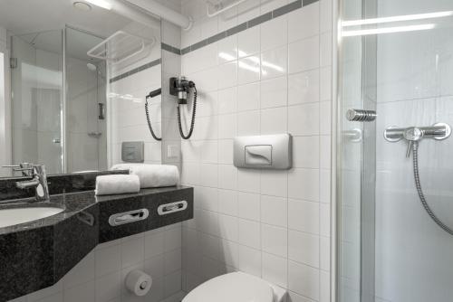 y baño con ducha, aseo y lavamanos. en IntercityHotel Kiel en Kiel