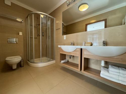 uma casa de banho com um lavatório, um chuveiro e um WC. em Greno Hotel & Spa em Karpacz