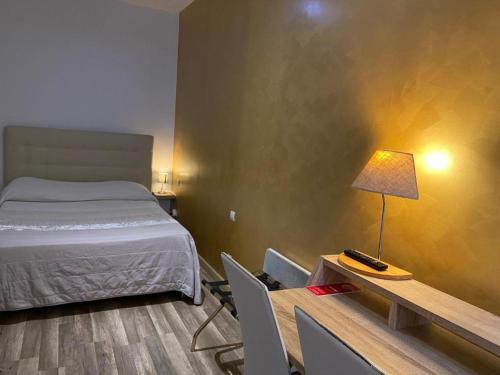 a bedroom with a bed and a desk with a lamp at Hotel Citadelle in Béziers