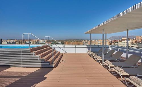 eine Terrasse mit Stühlen und ein Pool auf einem Gebäude in der Unterkunft NH Alicante in Alicante