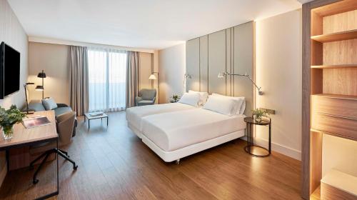Pokój hotelowy z białym łóżkiem i biurkiem w obiekcie NH Alicante w Alicante