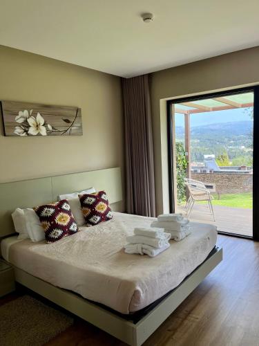 a bedroom with a large bed with a large window at Bosque da Harmonia in Arco de Baúlhe