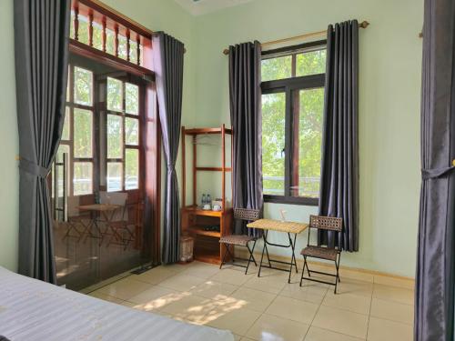 a bedroom with a table and chairs and windows at Vi TamCoc Hotel in Ninh Binh