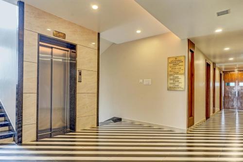 een lobby met een lift, een glazen deur en gestreepte vloeren bij Palette - Hotel Ocean Breeze in Bhopal