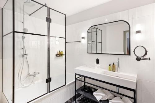 a bathroom with a shower and a sink and a mirror at Hotel Astoria Vienna, Curio Collection by Hilton in Vienna