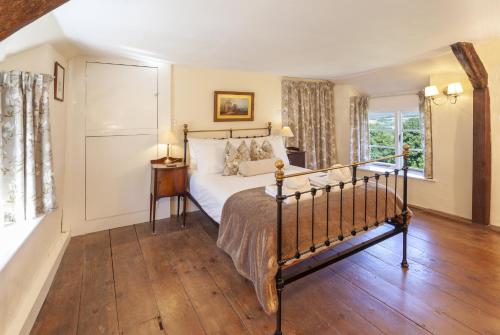 een slaapkamer met een bed en een houten vloer bij Syms Cottage Cutcombe in Cutcombe