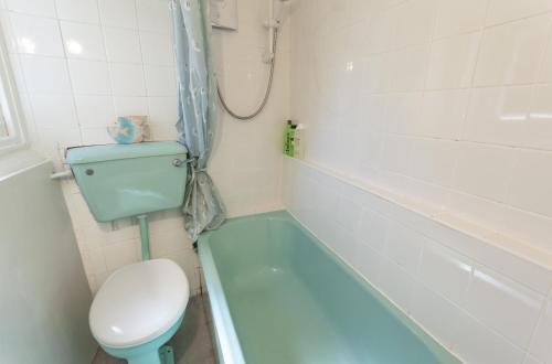 Syms Cottage Cutcombe في Cutcombe: حمام مع حوض استحمام أزرق ومرحاض ومغسلة