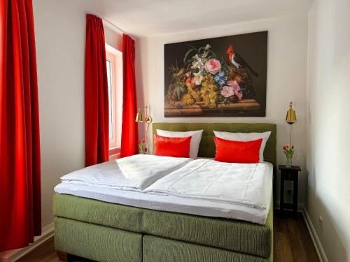 a bedroom with a bed with red curtains and a painting at Ferienwohnungen Bullay in Bullay
