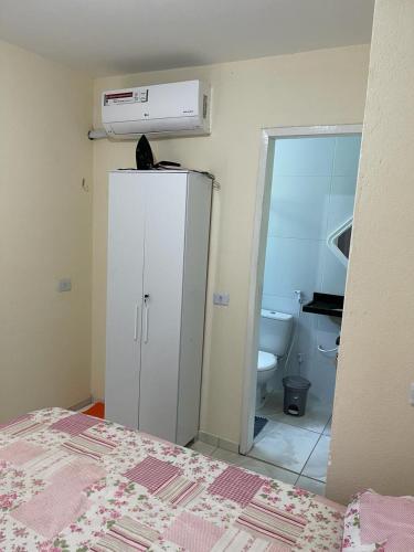 a bedroom with a white refrigerator and a bathroom at Casa 3 Quartos, 2 suites, piscina e sossego in São José da Coroa Grande