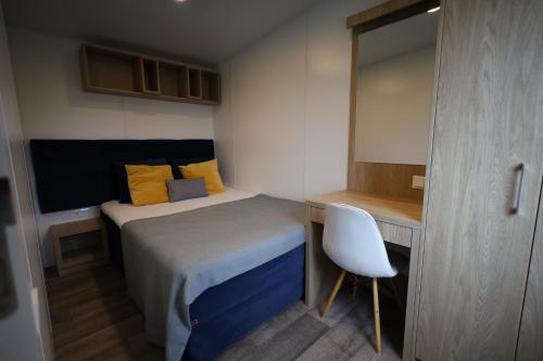a small bedroom with a bed and a desk at Mobilheim ECO in Borgdorf-Seedorf