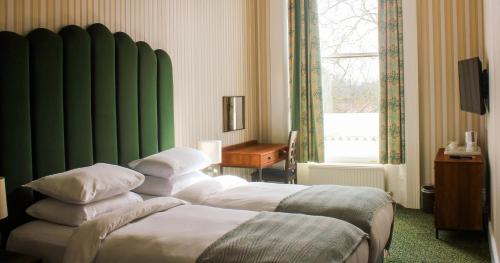 um quarto de hotel com duas camas e uma parede verde em The Columbia em Londres