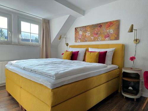 a bedroom with a large yellow bed with colorful pillows at Ferienwohnungen Bullay in Bullay