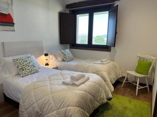 Cette chambre comprend deux lits, un canapé et une fenêtre. dans l'établissement Casa O Corvo, chalet cerca de Vigo en plena naturaleza, 