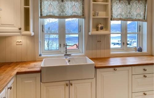 uma cozinha com um lavatório e duas janelas em Amazing Home In Eiksund With Kitchen 