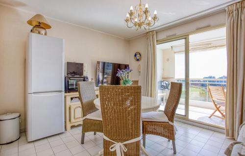 a kitchen with a white refrigerator and a table and chairs at Cozy Apartment In Mandelieu-La-Napoule in Mandelieu-la-Napoule