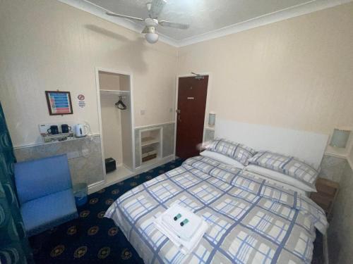 a bedroom with a bed and a blue chair at THE WILFORD HOTEL in Blackpool