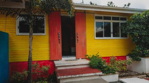 a yellow and red house with a red door at Villa Mitirapa in Tohautu