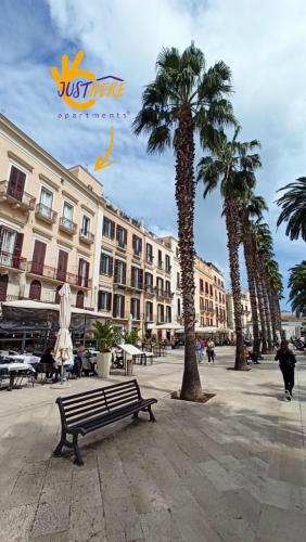 a bench in a plaza with palm trees and buildings at Just Here apartments - La mansarda in Bari