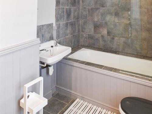 a bathroom with a tub and a sink and a toilet at Fuchsia Cottage in Sea Palling