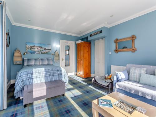 a bedroom with blue walls and a bed and a couch at The Old School House Annex in Tain