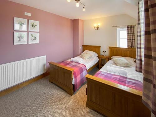 two beds in a room with purple walls at Cart-tws Bach - Om8 in Treffynnon 