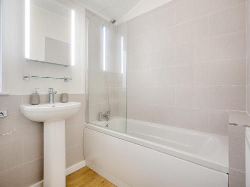 uma casa de banho branca com um lavatório, uma banheira e um WC. em Oak View Lodge em Llanrhaiadr