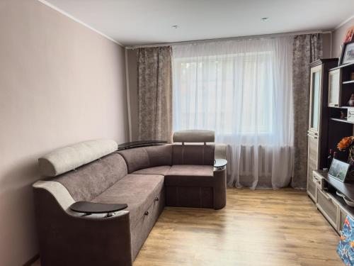 sala de estar con sofá marrón y ventana en Kalnu māja, en Krāslava