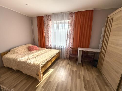 1 dormitorio con cama, escritorio y ventana en Kalnu māja, en Krāslava